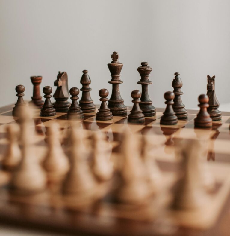 Close-up of a classic wooden chess set on a chessboard emphasizing the strategic game pieces.