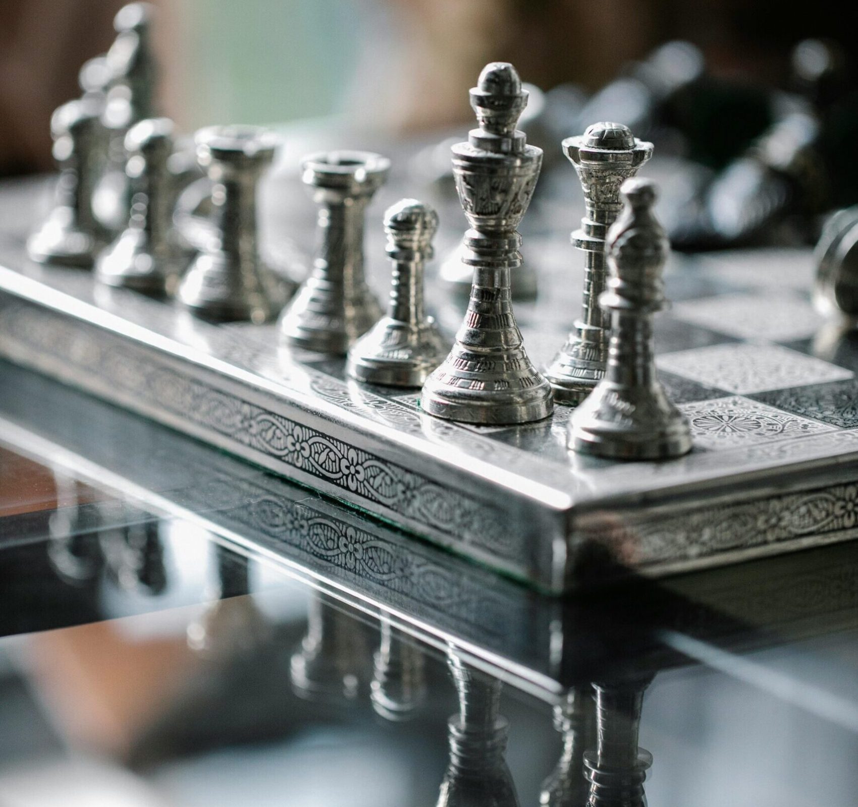 Classic metal chess board with set figurines designed with carved ornaments and placed on glass table in light room
